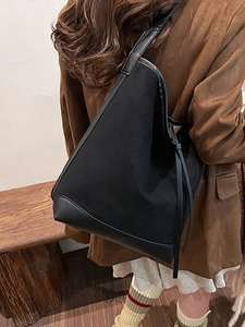 Minimalist black suede tote bag with leather trim shown on a model's shoulder