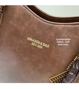 Detail of vintage brown leather tote bag featuring gold lettering and abacus metal charm