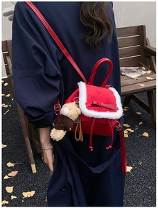 Close-up of red velvet backpack with white faux fur trim and cute bear charm outdoors
