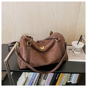 Détail d'un sac Boston en daim marron avec garniture dorée et bandoulière amovible