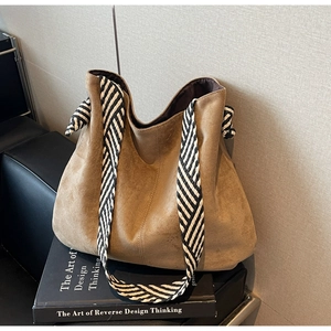 Detail view of brown suede tote bag with woven shoulder strap and knot design