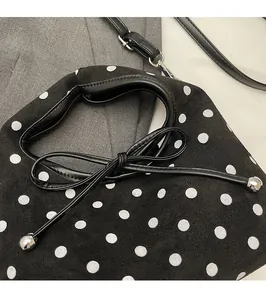 Détail du sac à pois noirs avec nœud en cuir et sphère décorative en métal argenté