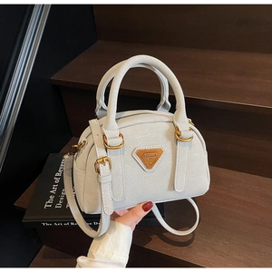 Detail of light gray lychee grain leather bowling bag with vintage gold metal hardware