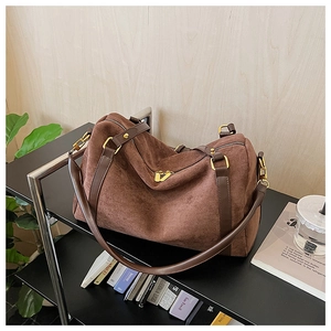 Détail de la texture en daim marron et des finitions dorées du sac Boston spacieux