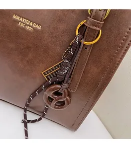 Detail of vintage brown tote featuring a woven charm and gold abacus pendant