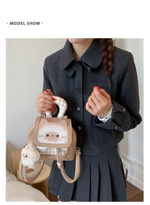 Detail of khaki cat print backpack with checkered handles and plush white charm