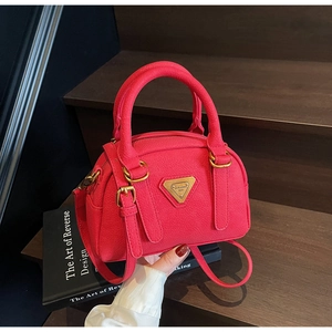 Detail of rose pink pebbled leather mini bowling bag with gold triangular metal plaque