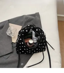 Vue détaillée de l'intérieur spacieux d'un sac à main noir à pois avec des cosmétiques