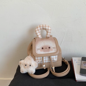 Close-up of a brown cartoon cat backpack featuring a plaid handle and star pendant