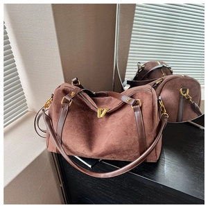Détail du sac Boston en daim marron foncé avec poignées en cuir et double zip doré brillant
