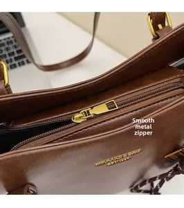 Detail of premium brown leather bag showing smooth gold metal zipper and brand logo