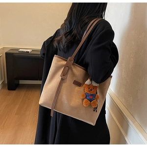 Detail of camel suede tote bag with brown leather straps and cute bear pendant charm