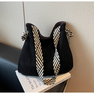 Detail of black matte hobo bag featuring a knotted black and white woven shoulder strap