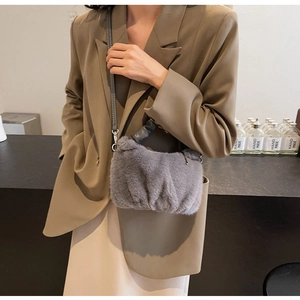 Détail d'un sac à main en peluche grise avec bandoulière sur modèle en blazer olive
