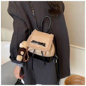 Detail view of khaki plush and black leather mini backpack with a bear pendant and bow