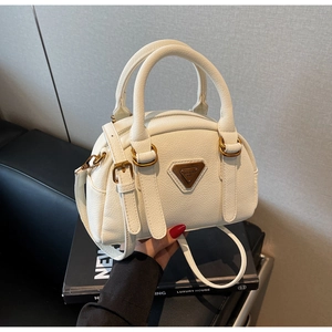 Close-up of white lychee textured Boston bag with vintage gold triangular logo plate