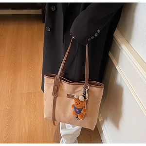 Brown faux suede tote bag with leather handles and a cute teddy bear charm on model