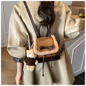 Detail of mini bucket backpack featuring brown leather panels and plush fur trim with bow