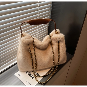 Détail du sac à main en fausse fourrure beige avec anses en cuir brun et chaîne dorée