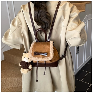 Detailed back view of a brown suede backpack with fur trim and a cute teddy bear charm