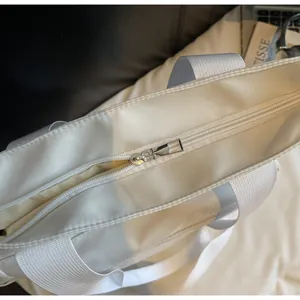 Gros plan sur la fermeture éclair en métal argenté d'un sac cabas en nylon blanc cassé