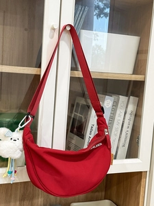 Borsa a tracolla in nylon rosso a mezzaluna con logo bianco e ciondolo a forma di orsetto