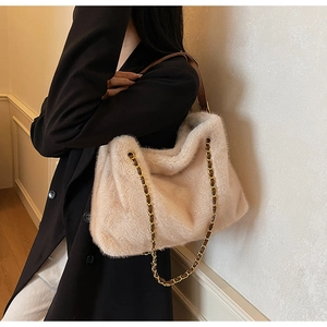 Détail du fourre-tout en fausse fourrure beige avec des bretelles en chaîne dorée tressée