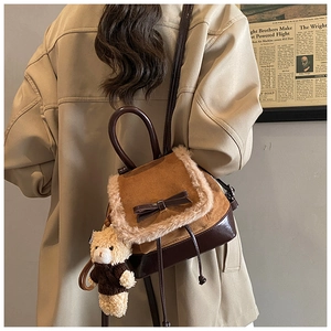Detailed close-up of brown corduroy backpack with plush fur trim and bear charm