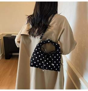 Détail du sac à pois avec cordon nœud papillon et fine bandoulière en cuir noir