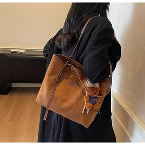 Macro view of brown matte suede tote bag with leather strap and cute bear charm