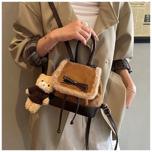 Close-up of brown suede mini backpack with plush trim, bow detail, and bear pendant