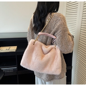 Sac à épaule en fausse fourrure rose avec chaîne dorée, porté par un mannequin