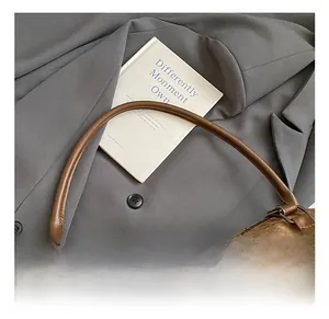Detail view of comfortable brown leather handles and sturdy metal rings on the canvas bag