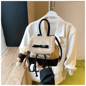 Detail of mini backpack featuring beige frosted texture with black fur and bow decoration