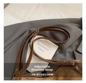 Detail of adjustable leather strap and silver metal buckle on brown corduroy bag