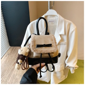 Detail of plush beige bucket backpack with black bow and cute brown bear keychain accessory