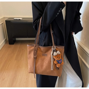 Brown frosted suede tote bag with cute bear charm worn over the shoulder by a model