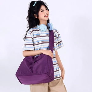 Detail view of large purple nylon drawstring bag showing side pockets and large capacity