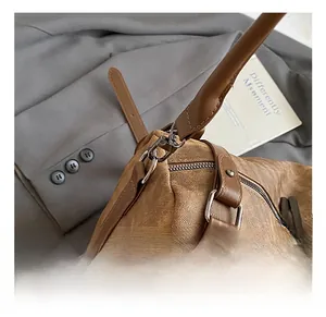 Detailed close-up of retro brown shoulder bag with silver metal D-ring and spring hook