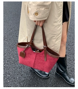 Detail of red suede tote bag with brown leather straps and a heart pendant in outdoor use