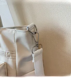 Détail des crochets en métal brillant et de la bandoulière de ce sac cabas épuré