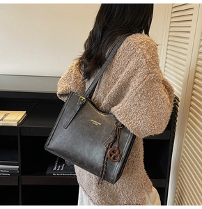 Detail of vintage black leather tote bag featuring brand logo and brown geometric charm