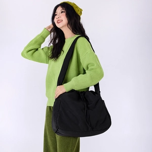 Detail of large black drawstring crossbody bag with wide strap on a fashion model