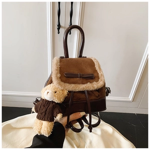 Detail of dark brown suede mini backpack with plush trim, bow, and bear keychain