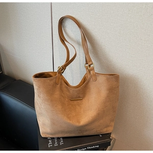 Detail van bruine matte leren shopper met gouden metalen strip op design boeken