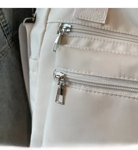 Détail des fermetures éclair argentées et du tissu en toile blanc cassé d'un grand sac