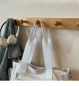 Détail d'un sac cabas blanc en nylon avec bandoulière large et poche zippée en métal