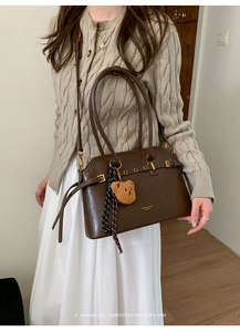 Détail du sac à main vintage marron foncé avec boucle dorée, ours et foulard rayé