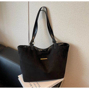 Detail van zwarte matte shopper tas met minimalistische gouden metalen strip en glanzende riem