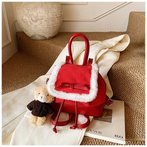 Detail of red bucket backpack with white plush trim, bow accent and cute bear pendant
